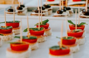 Circular bread cut-outs topped with slices of tomato and basil held together with a toothpick.