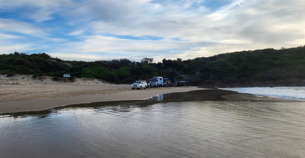 Vehicles parked on the beach near the tide line.